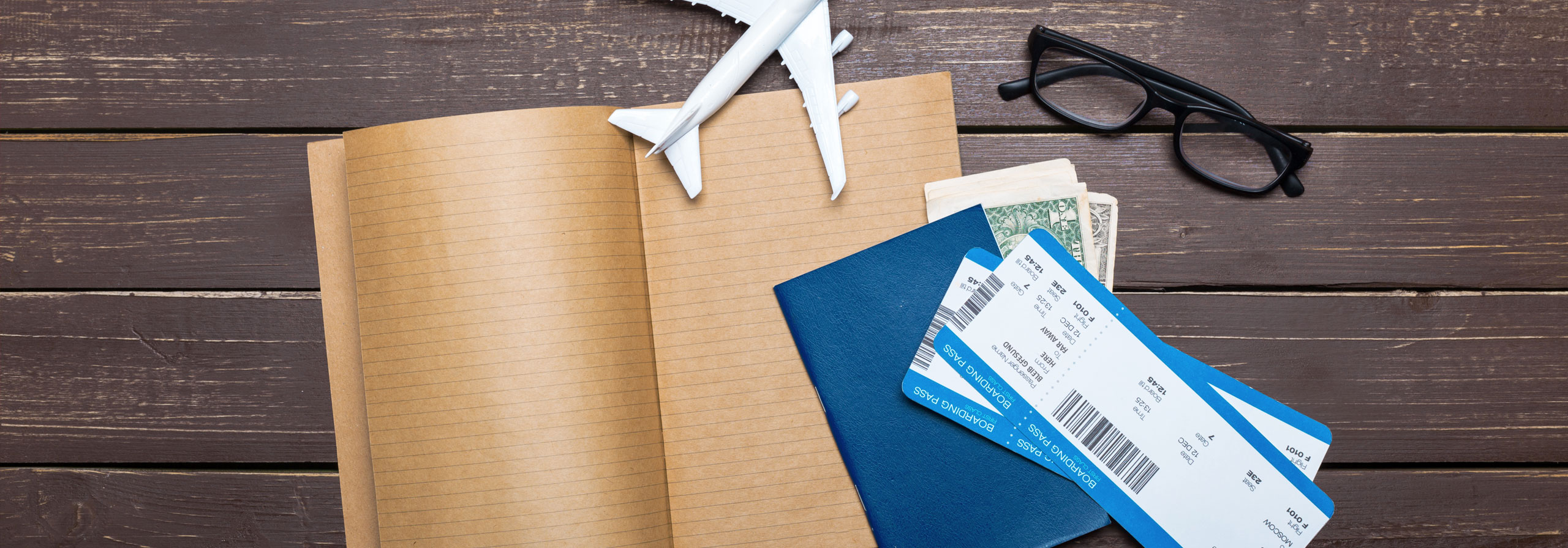 Flugtickets, Pass und Reisetagebuch auf einem Holzboden